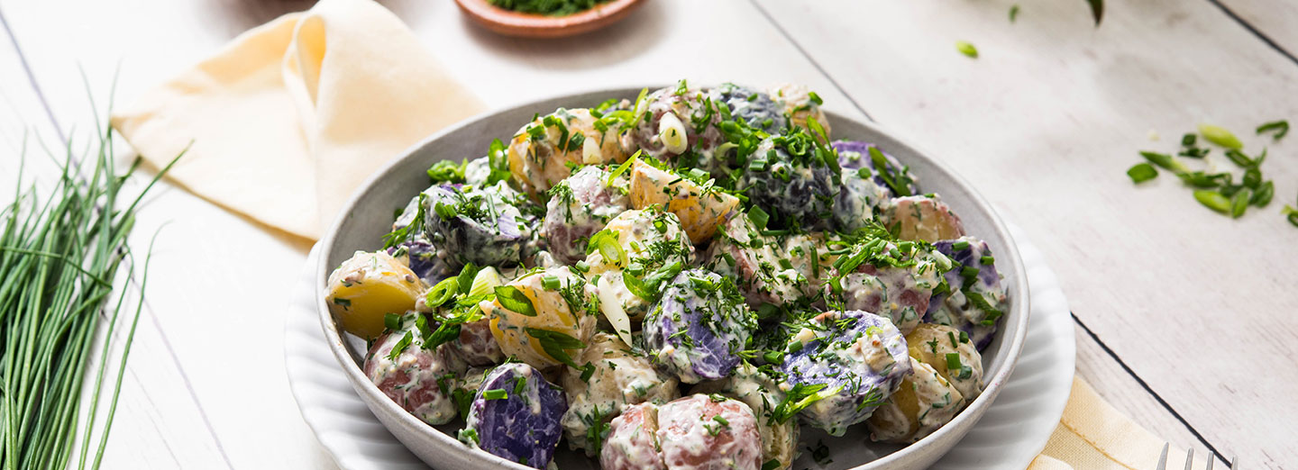 herbed potato salad in bowl on wooden table