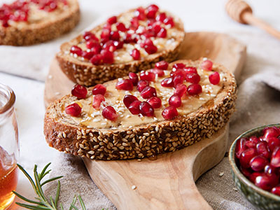 toast with peanut butter, pomegranate seeds and rosemary honey on top