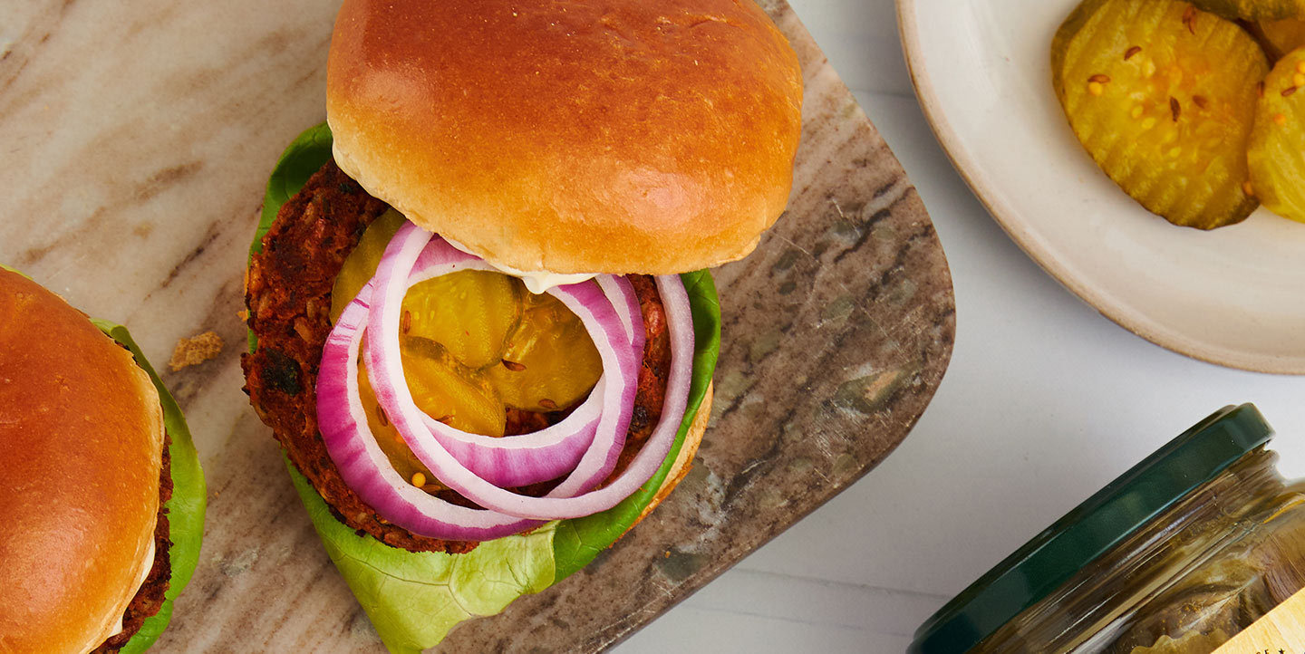 spicy veggie burger topped with onion resting on lettuce on a bun